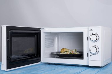 Gıda Isıtma için mavi bir ahşap yüzey üzerinde beyaz mikrodalga fırın