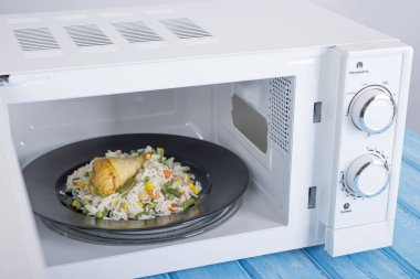 Gıda Isıtma için mavi bir ahşap yüzey üzerinde beyaz mikrodalga fırın