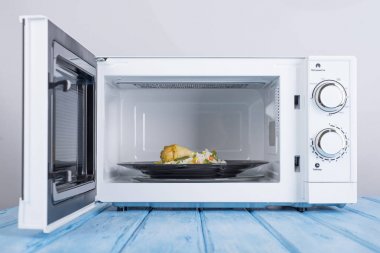 Gıda Isıtma için mavi bir ahşap yüzey üzerinde beyaz mikrodalga fırın