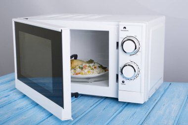 Gıda Isıtma için mavi bir ahşap yüzey üzerinde beyaz mikrodalga fırın