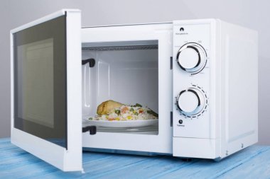 Gıda Isıtma için mavi bir ahşap yüzey üzerinde beyaz mikrodalga fırın