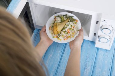 Gıda Isıtma için mavi bir ahşap yüzey üzerinde beyaz mikrodalga fırın