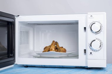 Gıda Isıtma için mavi bir ahşap yüzey üzerinde beyaz mikrodalga fırın