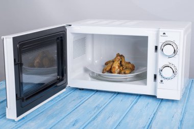 Gıda Isıtma için mavi bir ahşap yüzey üzerinde beyaz mikrodalga fırın