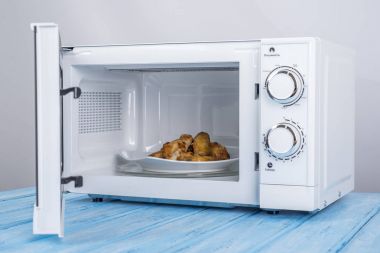 Gıda Isıtma için mavi bir ahşap yüzey üzerinde beyaz mikrodalga fırın