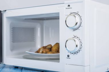 Gıda Isıtma için mavi bir ahşap yüzey üzerinde beyaz mikrodalga fırın