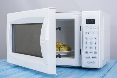 Gıda Isıtma için mavi bir ahşap yüzey üzerinde beyaz mikrodalga fırın