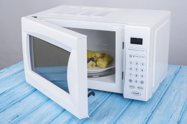 Gıda Isıtma için mavi bir ahşap yüzey üzerinde beyaz mikrodalga fırın