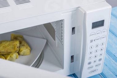 Gıda Isıtma için mavi bir ahşap yüzey üzerinde beyaz mikrodalga fırın