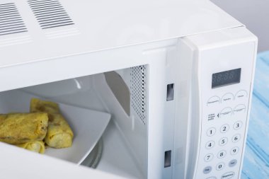 Gıda Isıtma için mavi bir ahşap yüzey üzerinde beyaz mikrodalga fırın