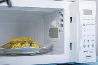 Gıda Isıtma için mavi bir ahşap yüzey üzerinde beyaz mikrodalga fırın