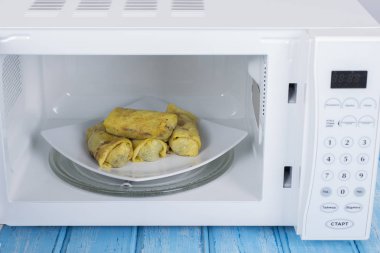 Gıda Isıtma için mavi bir ahşap yüzey üzerinde beyaz mikrodalga fırın