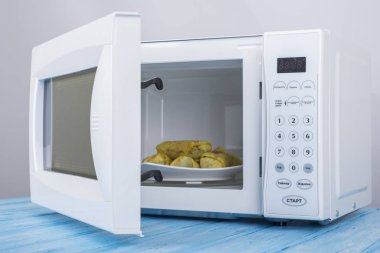 Gıda Isıtma için mavi bir ahşap yüzey üzerinde beyaz mikrodalga fırın