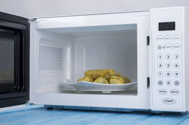 Gıda Isıtma için mavi bir ahşap yüzey üzerinde beyaz mikrodalga fırın