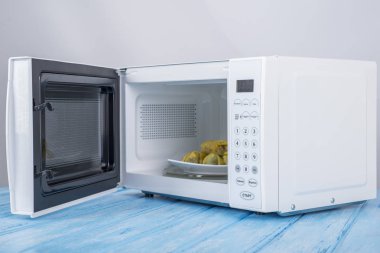 Gıda Isıtma için mavi bir ahşap yüzey üzerinde beyaz mikrodalga fırın