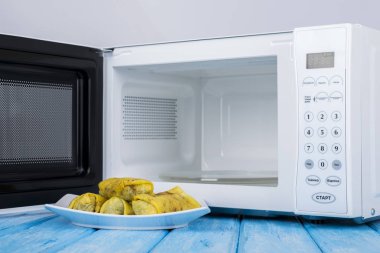 Gıda Isıtma için mavi bir ahşap yüzey üzerinde beyaz mikrodalga fırın