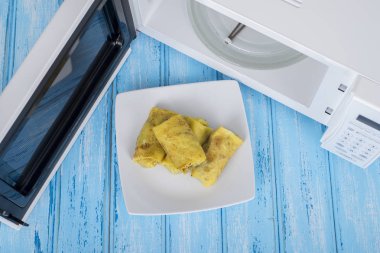 Gıda Isıtma için mavi bir ahşap yüzey üzerinde beyaz mikrodalga fırın