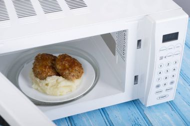 Gıda Isıtma için mavi bir ahşap yüzey üzerinde beyaz mikrodalga fırın