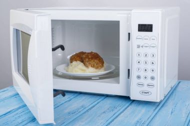 Gıda Isıtma için mavi bir ahşap yüzey üzerinde beyaz mikrodalga fırın