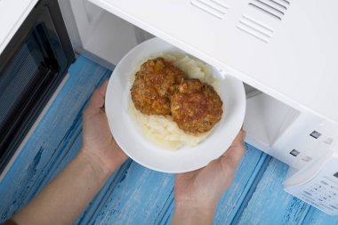 Gıda Isıtma için mavi bir ahşap yüzey üzerinde beyaz mikrodalga fırın