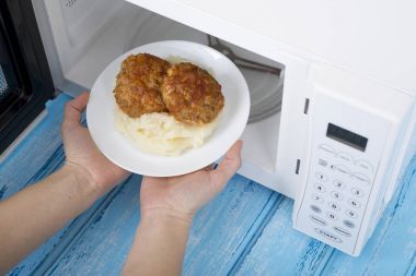 Gıda Isıtma için mavi bir ahşap yüzey üzerinde beyaz mikrodalga fırın