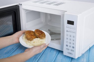 Gıda Isıtma için mavi bir ahşap yüzey üzerinde beyaz mikrodalga fırın