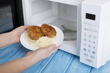 Gıda Isıtma için mavi bir ahşap yüzey üzerinde beyaz mikrodalga fırın