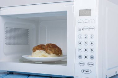 Gıda Isıtma için mavi bir ahşap yüzey üzerinde beyaz mikrodalga fırın