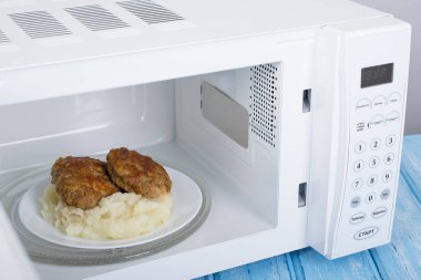 Gıda Isıtma için mavi bir ahşap yüzey üzerinde beyaz mikrodalga fırın