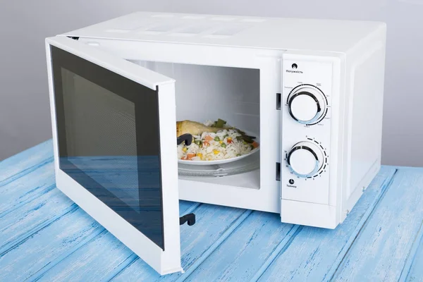 white microwave oven, on a blue wooden surface for heating food