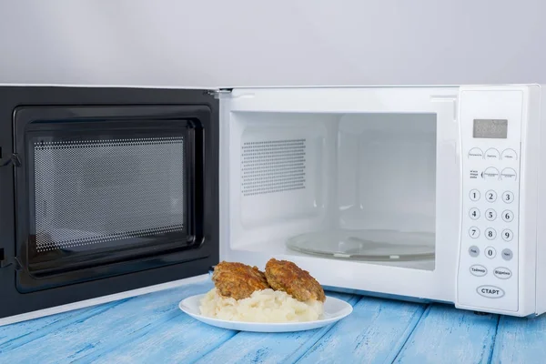 Белая микроволновая печь, на голубой деревянной поверхности для нагрева пищи — стоковое фото