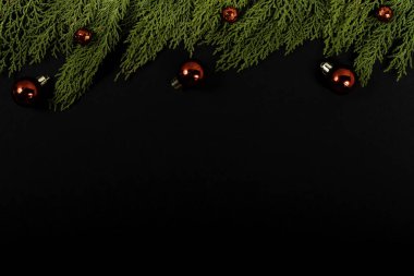 Noel kompozisyonu. Siyah arka planda kırmızı Noel süsleri olan Girlanda. Noel, kış, yeni yıl konsepti. Düz konum, üst görünüm, kopyalama alanı.