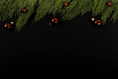 Noel kompozisyonu. Siyah arka planda kırmızı Noel süsleri olan Girlanda. Noel, kış, yeni yıl konsepti. Düz konum, üst görünüm, kopyalama alanı.