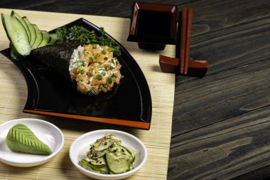 Siyah arka planda siyah tabakta somon temaki suşisi. Japon mutfağı..