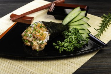 Siyah arka planda siyah tabakta somon temaki suşisi. Japon mutfağı..