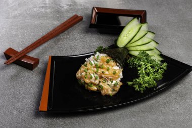 Siyah arka planda siyah tabakta somon temaki suşisi. Japon mutfağı..