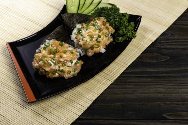 Siyah arka planda siyah tabakta somon temaki suşisi.