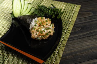 Siyah arka planda siyah tabakta somon temaki suşisi. Japon mutfağı..