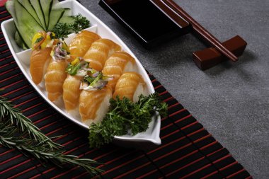 Siyah tekne şeklinde birkaç tane somon balığı. Gri taş arka plan. Japon gıda konsepti.