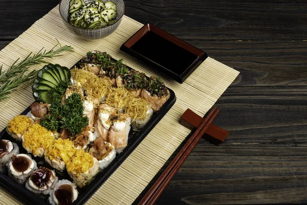 Full plate of sushi for delivery on black wooden background