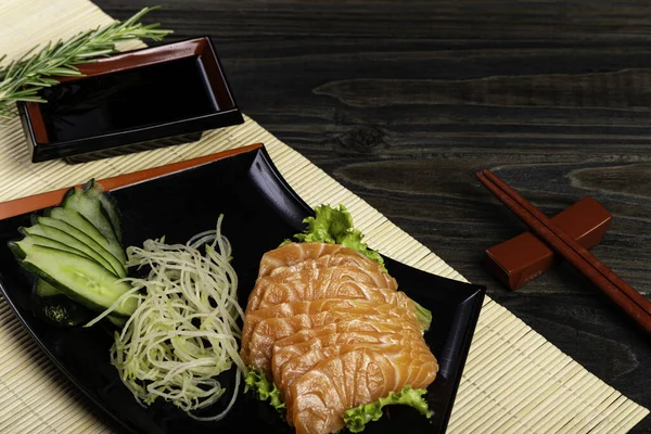 Fresh salmon fish at restaurant very delicious. Japanese foods sashimi on black wood background.