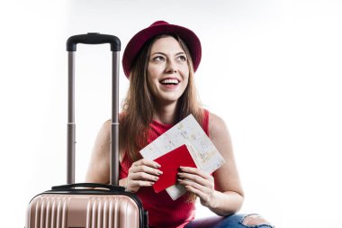 Günlük kıyafetlerle gezen turist kadın portresi, beyaz arka planda bavulu olan şapka. Hava yolculuğu konsepti.