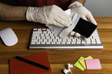 Eldivenli adam salgın sırasında cep telefonu temizliği yapıyor. (covid-19, 2019-CoV, SARS).