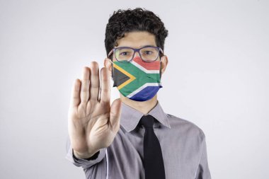 Güney Afrika bayrağıyla maskeli bir adam sosyal mesafeyi korumak istiyor. Covid-19, SARS-CoV-2. Sosyal uzaklık kavramı.