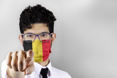 Man in mask with flag of Belgium pointing at you. Stay at home concept. clipart