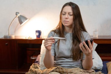 Şiddetli grip sırasında yatağında ateşini ölçen modelin ayrıntıları. Hastalıklı kavram.