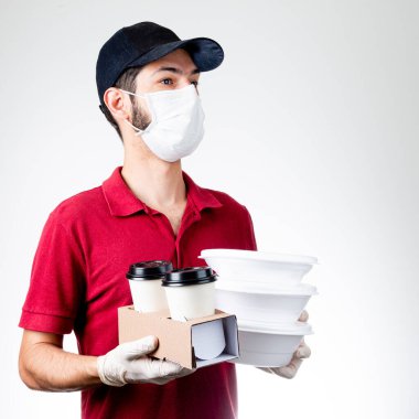 Siyah şapkalı, eldivenli, maskeli beslenme çantası ya da beslenme çantası taşıyan ve teslimat için içen bir teslimatçı. dağıtım konsepti.
