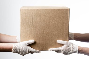 Teslimatçı, müşteriye bir kutu mal teslim ediyor. Gri arkaplanda teslimat kavramı.