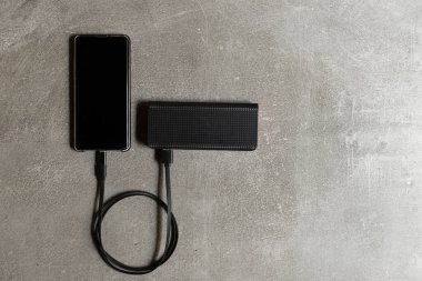 Şarj sırasında cep telefonunun beton arka planı. Ekstra pil kavramı.