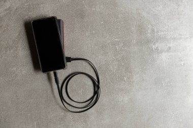 Çalışma masasında harici bataryası olan bir cep telefonu. Teknik Aygıt Paylaşımı.